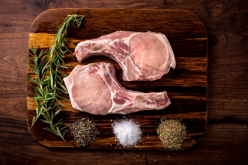 Grass Roots Farmers' Co-op forested pork on a cutting board with spices. Our pork offers more complex flavoring and Omega-3s